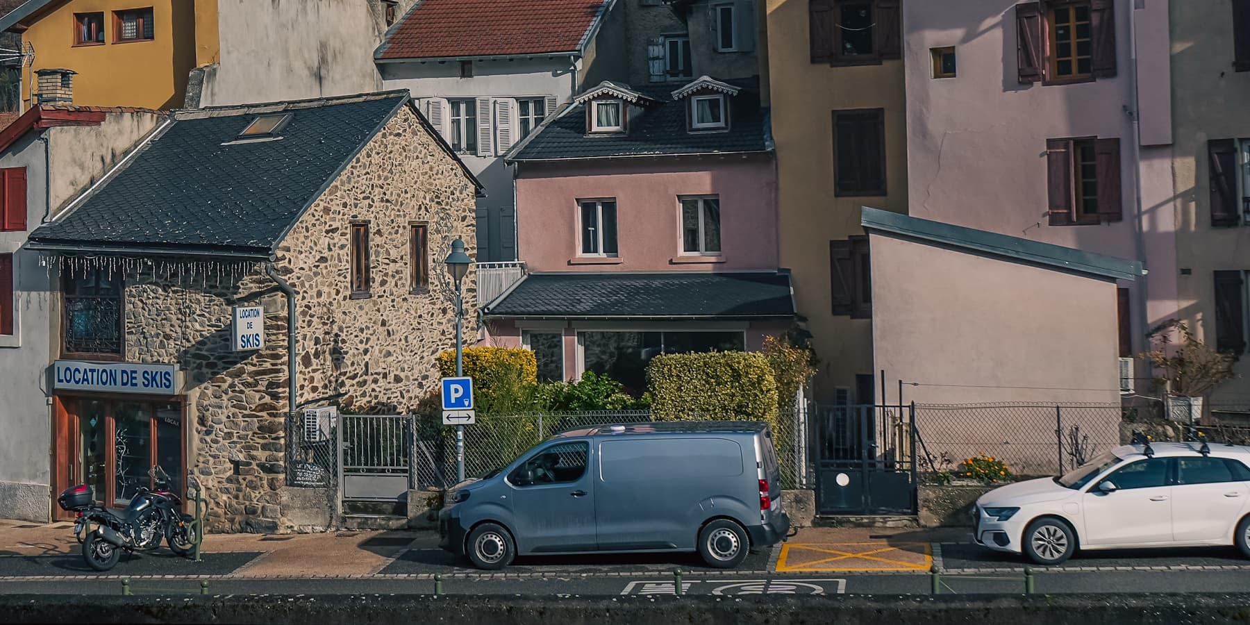 Stone houses and parked cars in a mountain town photographed by Eugene Truuts